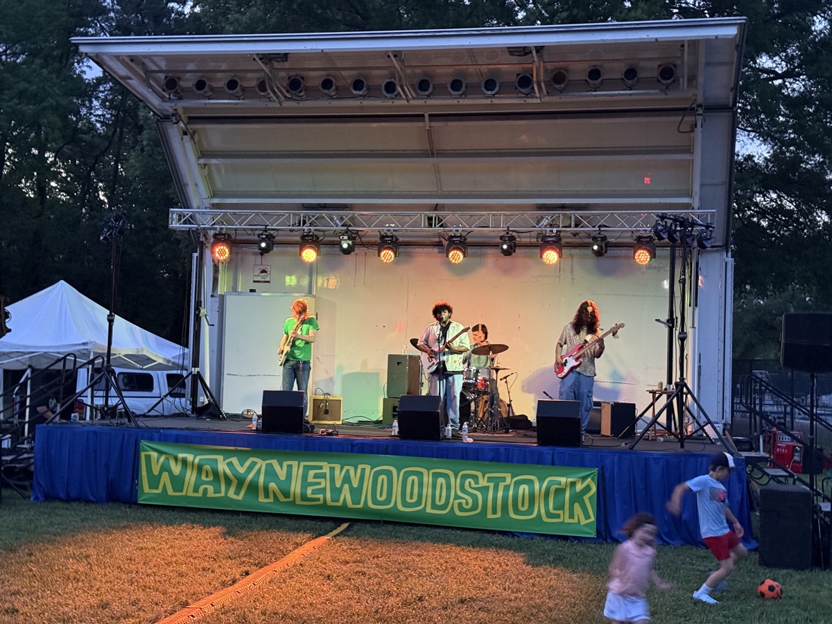Band performing on the Waynewoodstock stage at dusk with colorful lights